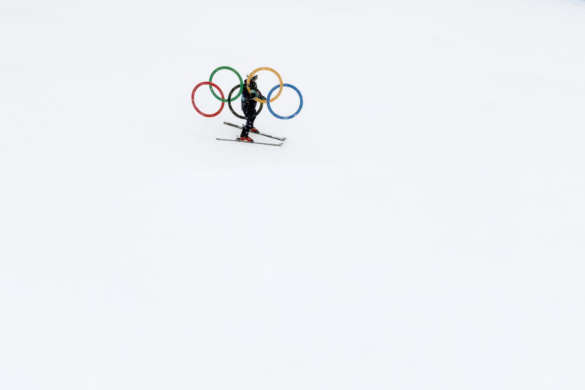 A construction worker carries the Olympic rings as he makes his way down a skicross course in Livigno, Italy, on Wednesday, February 4.