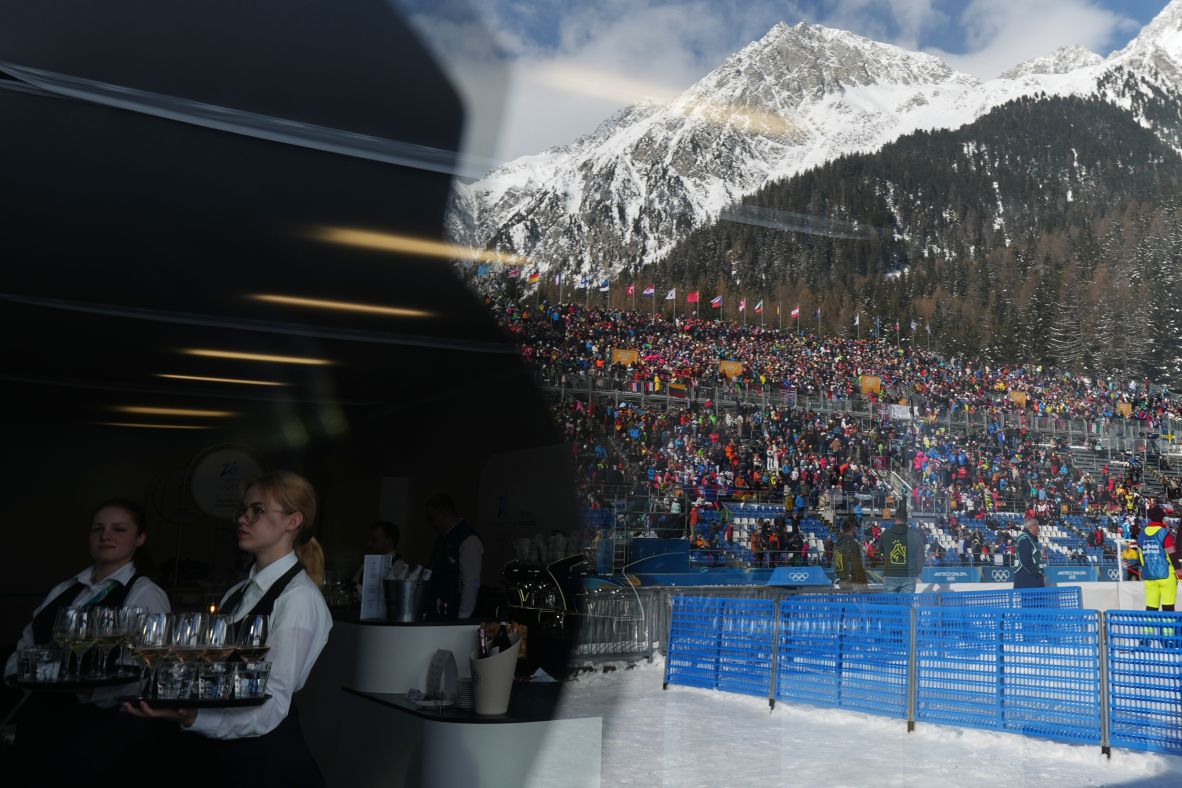 Waiters serve drinks as fans are reflected on a building ahead of the men's 15km mass start biathlon race on February 20.