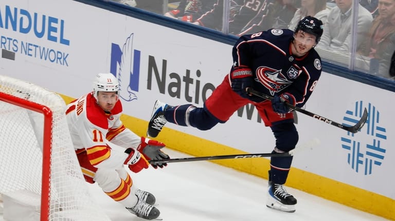 Columbus Blue Jackets' Zach Werenski, right, clears the puck past...