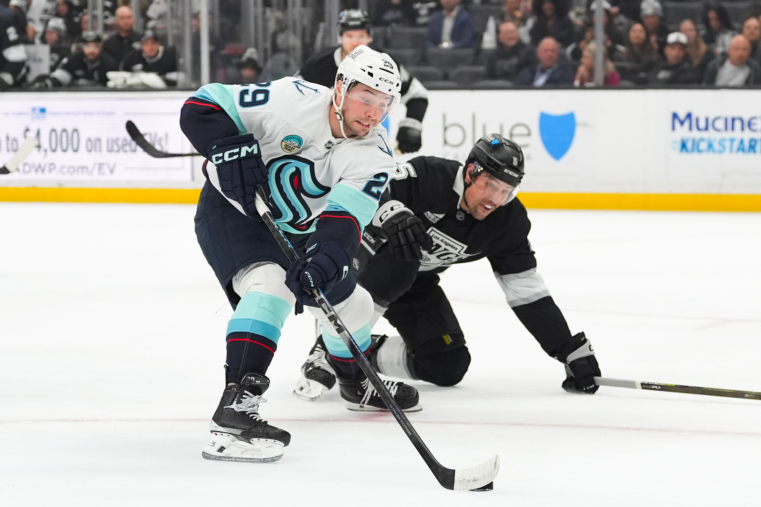 Seattle Kraken defenseman Vince Dunn, left, moves the puck past...
