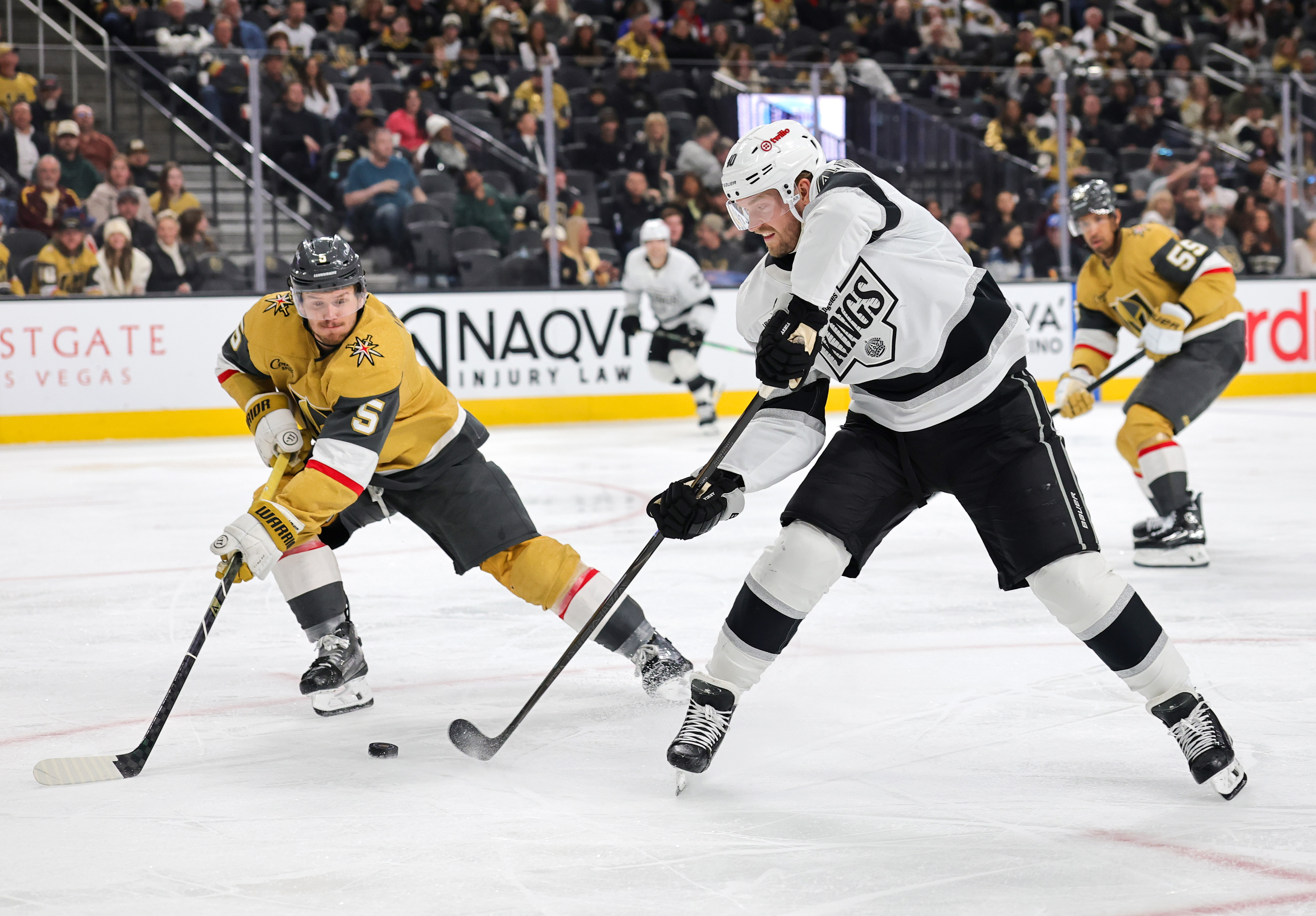 The Kings’ Corey Perry, right, passes the puck between the...