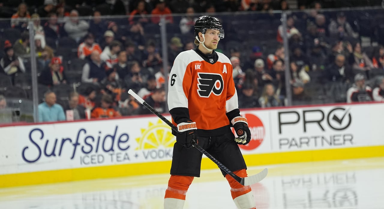 hockey player wearing an orange, white and black jersey stand on the ice
