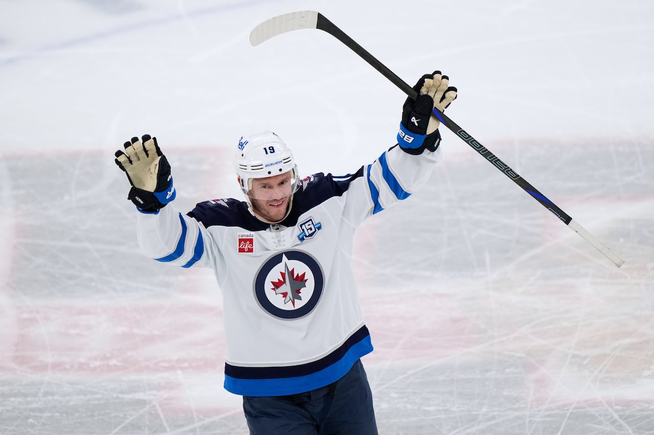 A Winnipeg Jets player smiles and raises his arms.