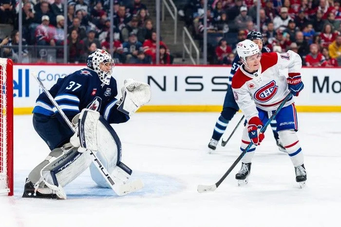  Cole Caufield of the Montreal Canadiens screens Connor Hellebuyck (#37) of the Winnipeg Jets in the first period at Canada Life Centre on February 4, 2026.