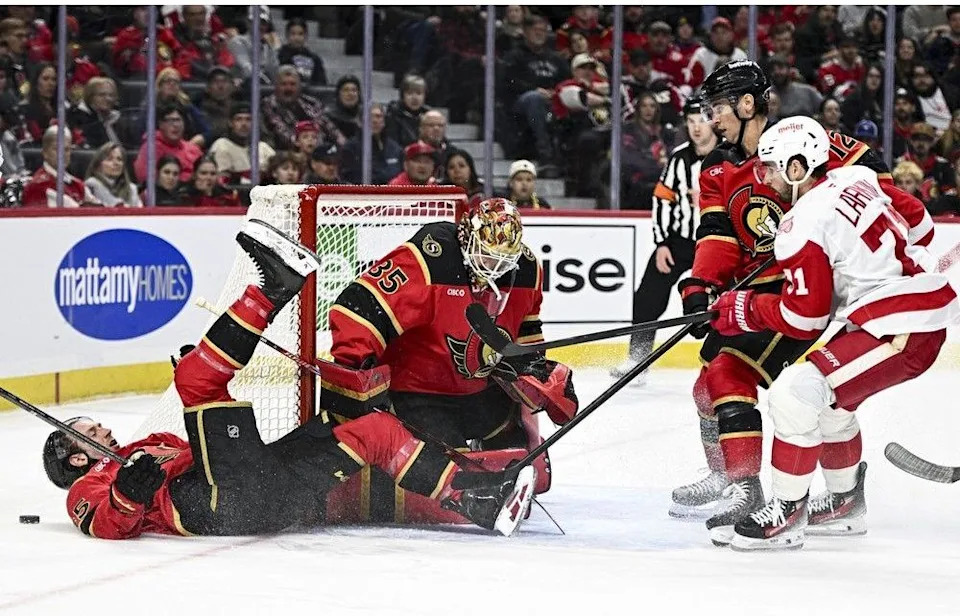 Senators defenceman Jake Sanderson (85) crashes to the ice in front of goaltender Linus Ullmark during the first period of Thursday’s home game against the Detroit Red Wings.