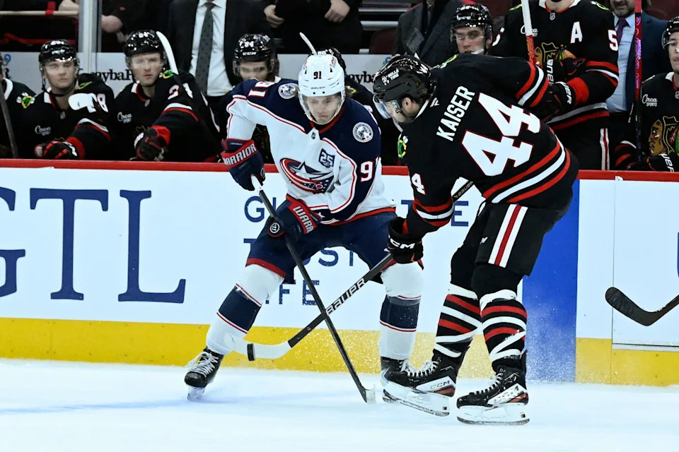 Jan 30, 2026; Chicago, Illinois, USA; Columbus Blue Jackets center Kent Johnson (91) and Chicago Blackhawks defenseman Wyatt Kaiser (44) chase the puck during the first period at the United Center. Mandatory Credit: Matt Marton-Imagn Images