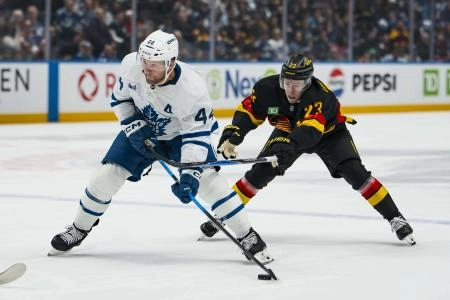 Jan 31, 2026; Vancouver, British Columbia, CAN; Vancouver Canucks forward Jonathan Lekkerimaki (23) stick checks Toronto Maple Leafs defenseman Morgan Rielly (44) in the first period at Rogers Arena
