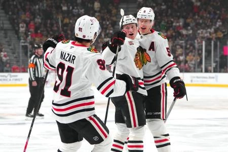 Dec 2, 2025; Las Vegas, Nevada, USA; Chicago Blackhawks center Oliver Moore (11) celebrates with defenseman Sam Rinzel (6) and center Frank Nazar (91) after scoring a goal against the Vegas Golden Knights during the first period at T-Mobile Arena.