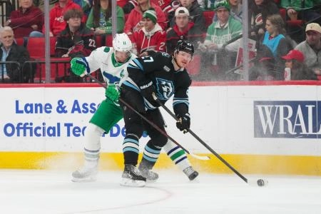 Jan 29, 2026; Raleigh, North Carolina, USA; Utah Mammoth center Barrett Hayton (27) truest control the puck against Carolina Hurricanes center Jordan Staal (11) during the first period at Lenovo Center.