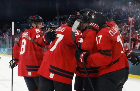Feb 13, 2026; Milan, Italy; Nathan MacKinnon of Canada celebrates with teammates after scoring their fifth goal against Switzerland in men's ice hockey group A play during the Milano Cortina 2026 Olympic Winter Games at Milano Santagiulia Ice Hockey Arena. Mandatory Credit: Geoff Burke-Imagn Images