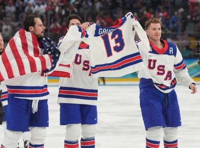 Feb 22, 2026; Milan, Italy; Auston Matthews (34) of the United States, Zach Werenski (8) of the United States and Matthew Tkachuk (19) of the United States hold up the jersey of John Gaudreau after defeating Canada in the men's ice hockey gold medal game during the Milano Cortina 2026 Olympic Winter Games at Milano Santagiulia Ice Hockey Arena.