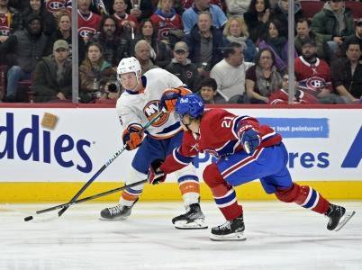Dec 16, 2023; Montreal, Quebec, CAN; New York Islanders forward Julien Gauthier (16) plays the puck and Montreal Canadiens defenseman Kaiden Guhle (21) defends during the first period at the Bell Centre.