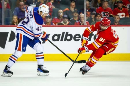 Feb 4, 2026; Calgary, Alberta, CAN; Calgary Flames center Nazem Kadri (91) and Edmonton Oilers right wing Kasperi Kapanen (42) battle for the puck during the third period at Scotiabank Saddledome.