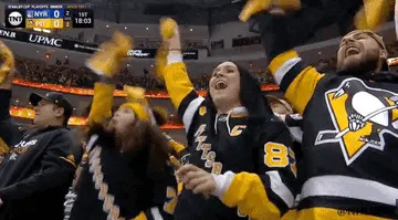 Hockey fans in jerseys enthusiastically wave towels during a game, expressing excitement and support for their team in a crowded arena