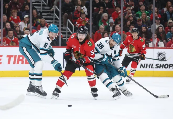 Feb 2, 2026; Chicago, Illinois, USA; Chicago Blackhawks left wing Tyler Bertuzzi (59), San Jose Sharks defenseman Vincent Desharnais (5) and defenseman Mario Ferraro (38) battle for control of the puck during the first period at United Center.