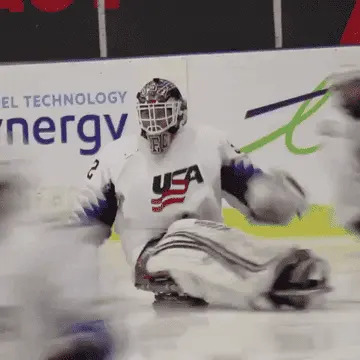 Hockey player in full gear, including a helmet and USA jersey, participates in a sled hockey game on the ice