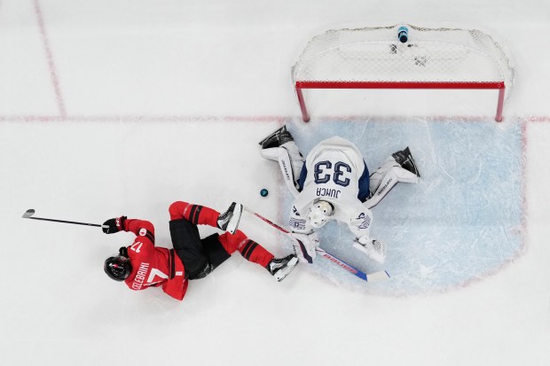 Canada's Macklin Celebrini (17) challenges France's goalkeeper Julian Junca (33) during a preliminary round game of men's ice hockey between Canada and France at the 2026 Winter Olympics, in Milan, Italy, Sunday, Feb. 15, 2026. (AP Photo/Carolyn Kaster)