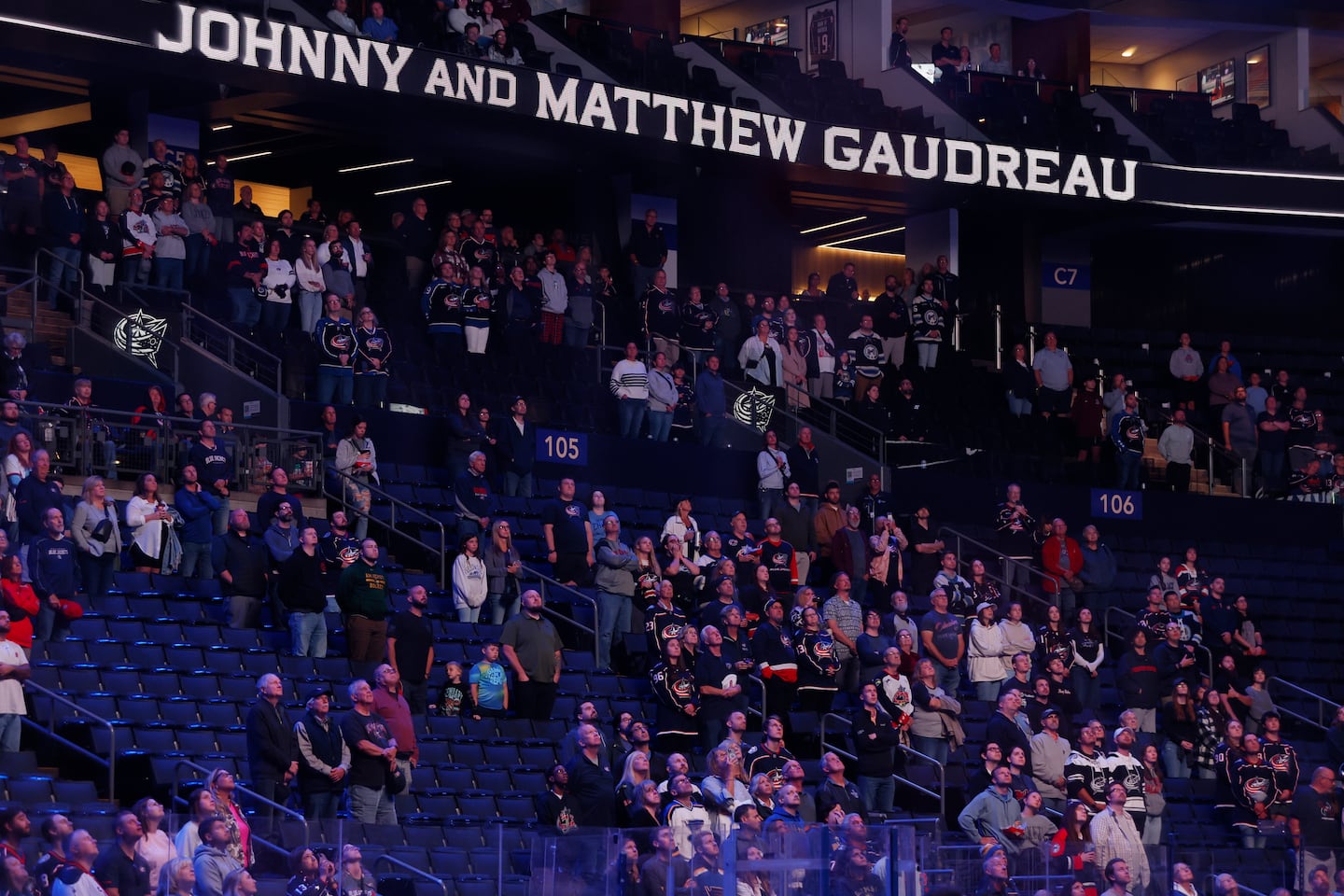 Fans stand for a 13-second moment of silence in memory of Columbus Blue Jackets' Johnny Gaudreau and his brother Matthew before the start of an NHL preseason hockey game against the St. Louis Blues, on Sept. 25, 2024, in Columbus, Ohio. The Gaudreau brothers were killed while riding their bicycles.