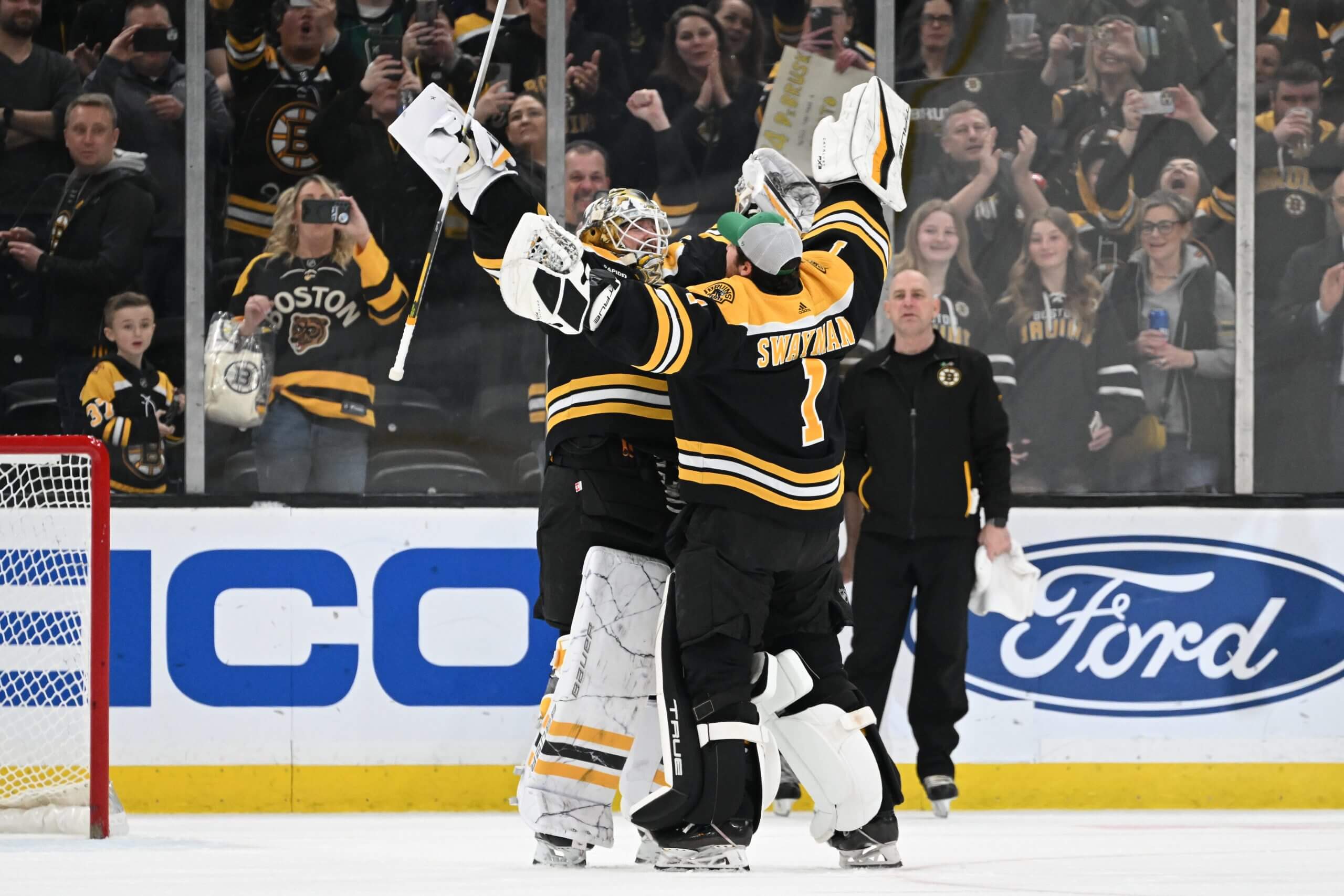 Linus Ullmark and Jeremy Swayman extend their arms in the air for a goalie hug during the Bruins' 2022-23 season.