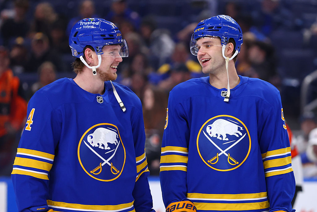 BUFFALO, NEW YORK - JANUARY 14: Bowen Byram #4 and Josh Norris #9 of the Buffalo Sabres share a laugh while warming up prior to an NHL game against the Philadelphia Flyers on January 14, 2026 at KeyBank Center in Buffalo, New York. (Photo by Bill Wippert/NHLI via Getty Images)