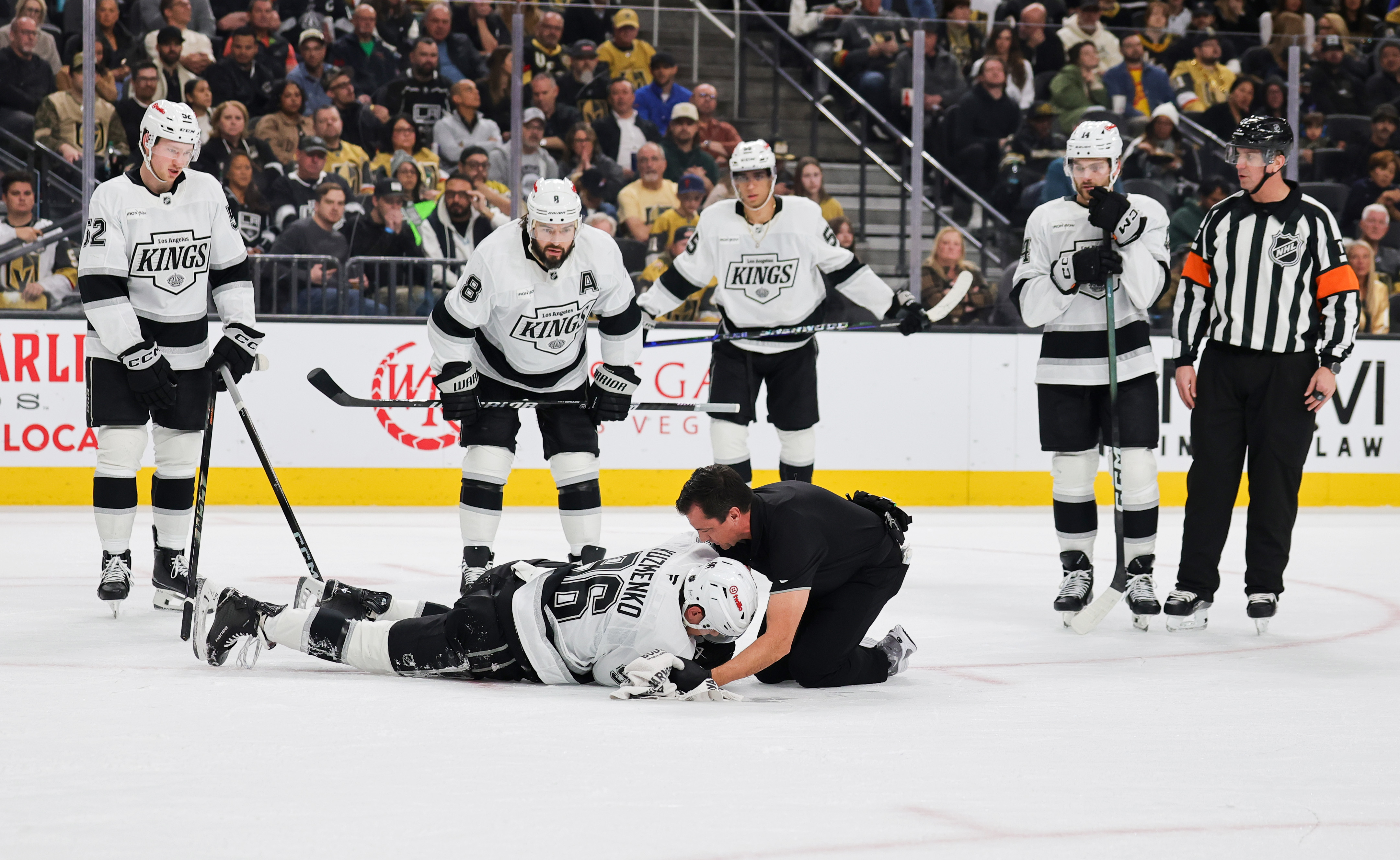 Kings teammates look on as Andrei Kuzmenko (96) is tended...