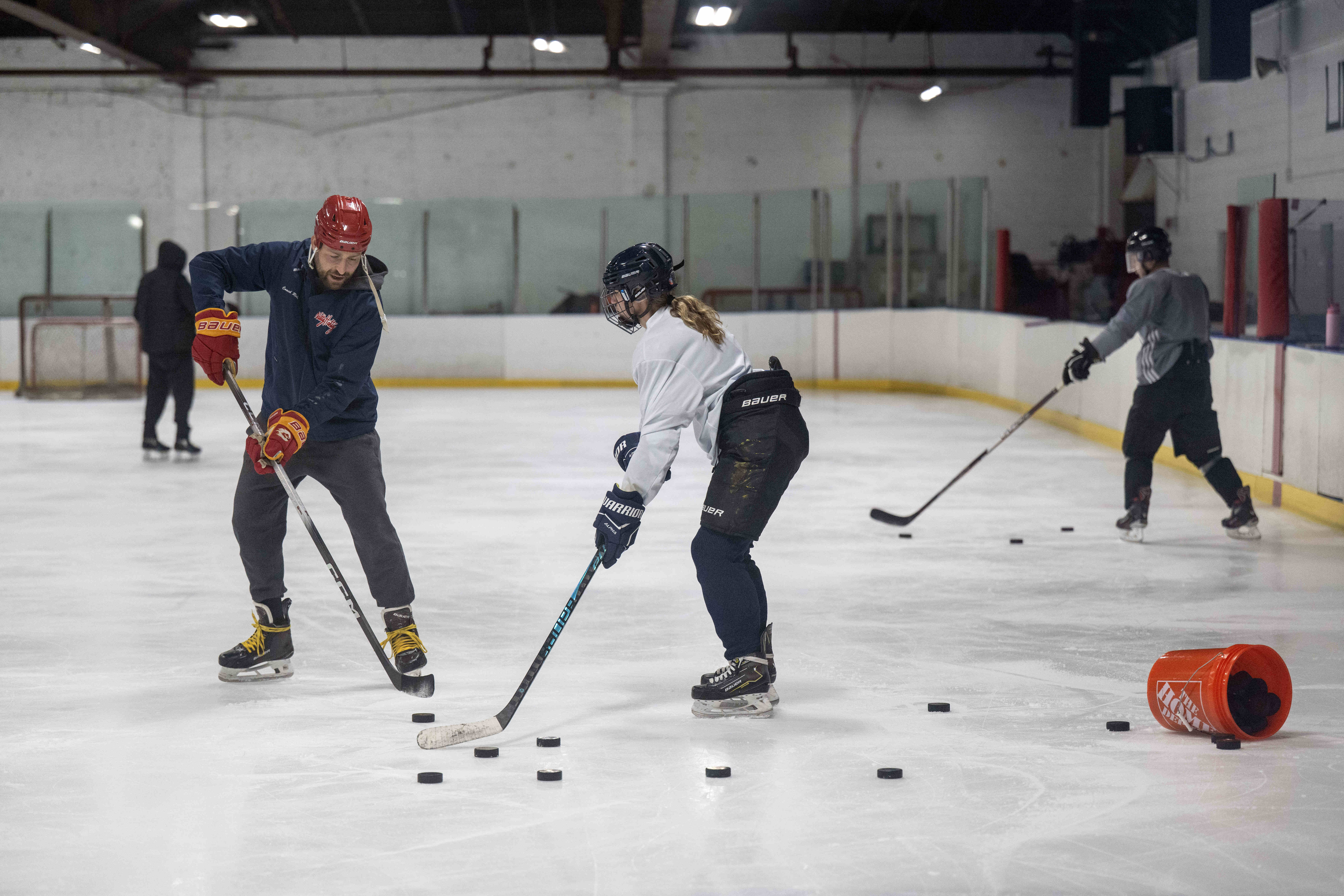 Coach Benjamin Rubin works with Lizzie Addington on her hockey...