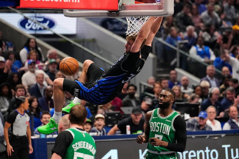 Dallas Mavericks forward Cooper Flagg hangs on the rim after dunking between Boston Celtics'...