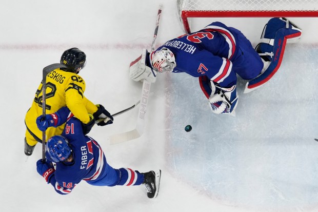 United States' goalkeeper Connor Hellebuyck (37) and Brock Faber (14) defend against Sweden's Gabriel Landeskog (92) during a men's ice hockey quarterfinal game between the United States and Sweden at the 2026 Winter Olympics, in Milan, Italy, Wednesday, Feb. 18, 2026. (AP Photo/Carolyn Kaster)