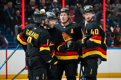 Vancouver Canucks forwards Elias Pettersson, Brock Boeser, and Conor Garland celebrate a goal