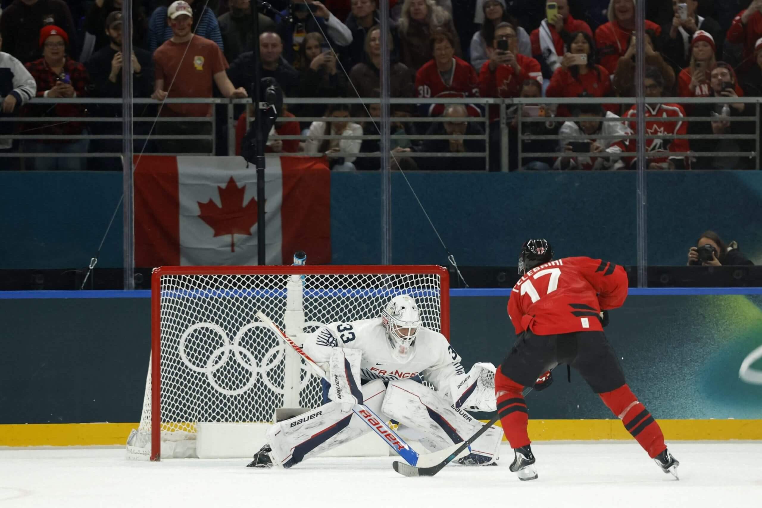 Macklin Celebrini, in red jersey, drives toward the net.