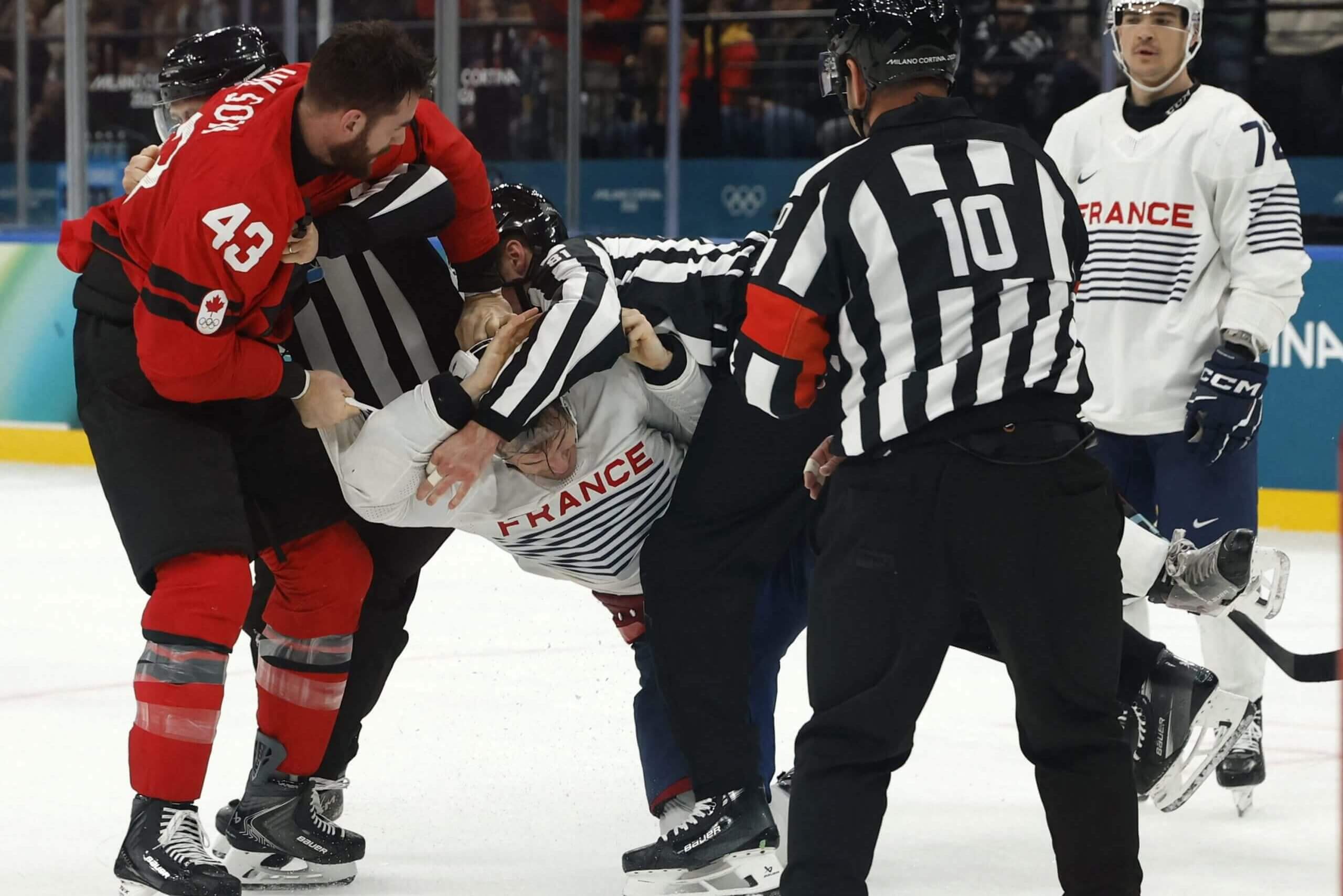 Tom Wilson scuffles with France's Pierre Crinon with referees trying to separate them and a France player looking on.