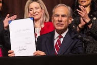 Texas Governor Greg Abbott holds up House Bill 4211, passed during the 89th Regular...