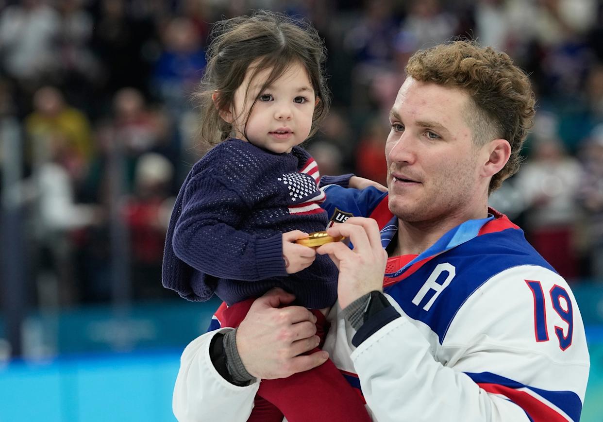 Petr David Josek/AP - PHOTO: USA's Matthew Tkachuk carries Noa Gaudreau after they defeated Canada to win the men's ice hockey gold medal at the Milano Cortina 2026 Winter Olympic Games in Milan, February 22, 2026.