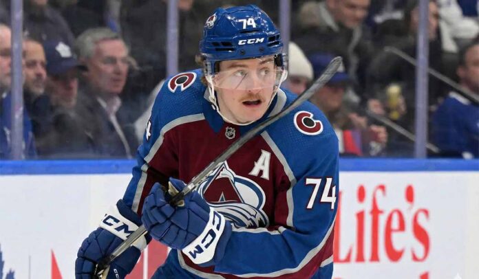 Colorado Avalanche forward Bobby McMann (74) looking up on the ice, wearing the team's maroon home jersey and a blue helmet during a game.