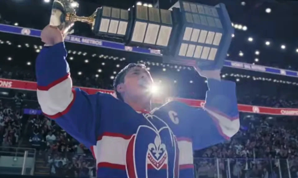 Shane from Heated Rivalry holding a trophy aloft on an ice rink, with a cheering crowd in the background