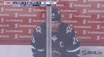 Hockey player in penalty box with helmet and team's jersey, looks into distance