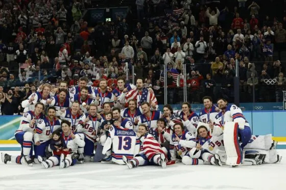 Feb 22, 2026; Milan, Italy; Team United States celebrate on the ice while holding a jersey of their late teammate Johnny Gaudreau after the medal ceremony during the Milano Cortina 2026 Olympic Winter Games at Milano Santagiulia Ice Hockey Arena. Mandatory Credit: Geoff Burke-Imagn Images