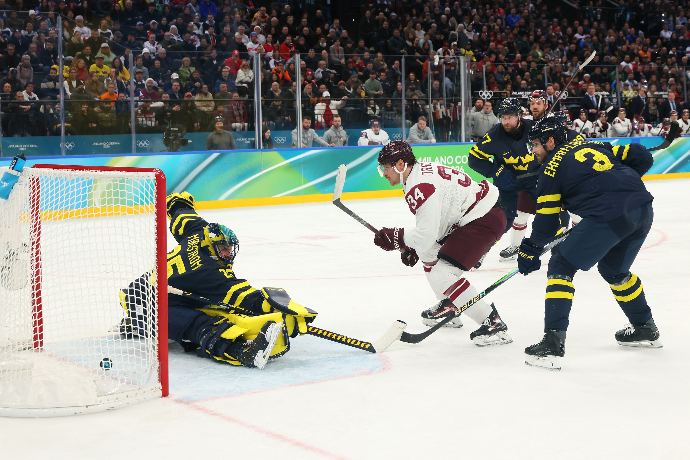 MILAN, ITALY - FEBRUARY 17: Eduards Tralmaks #34 of Team Latvia scores a goal against Jacob Markström #25 and Oliver Ekman-Larsson #3 of Team Sweden in the second period during the Men’s Qualification Playoff match between Sweden and Latvia on day 11 of the Milano Cortina 2026 Winter Olympic games at Milano Santagiulia Ice Hockey Arena on February 17, 2026 in Milan, Italy. (Photo by Bruce Bennett/Getty Images)