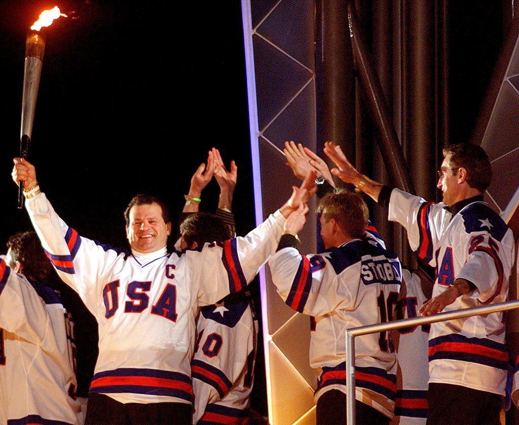 Members of the 1980 US gold medal-winning hockey team lighting the Olympic flame.