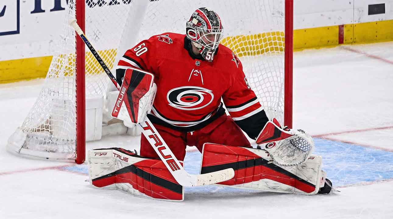 Carolina Hurricanes goaltender Jordan Binnington, wearing a red number 50 jersey and custom red, white, and black pads, positioned in a butterfly stance in front of the net.