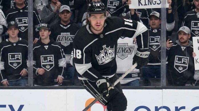 A visualization of hockey player Robert Thomas wearing a black No. 18 Los Angeles Kings jersey, skating intently on the ice while fans in casual clothing watch from behind the glass.
