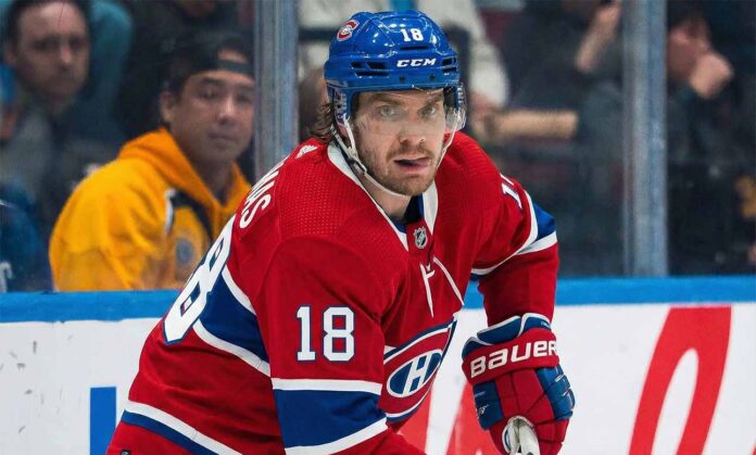 Montreal Canadiens center Robert Thomas (18), wearing the team's red home jersey and blue helmet, skates on the ice during a game, looking towards the camera.