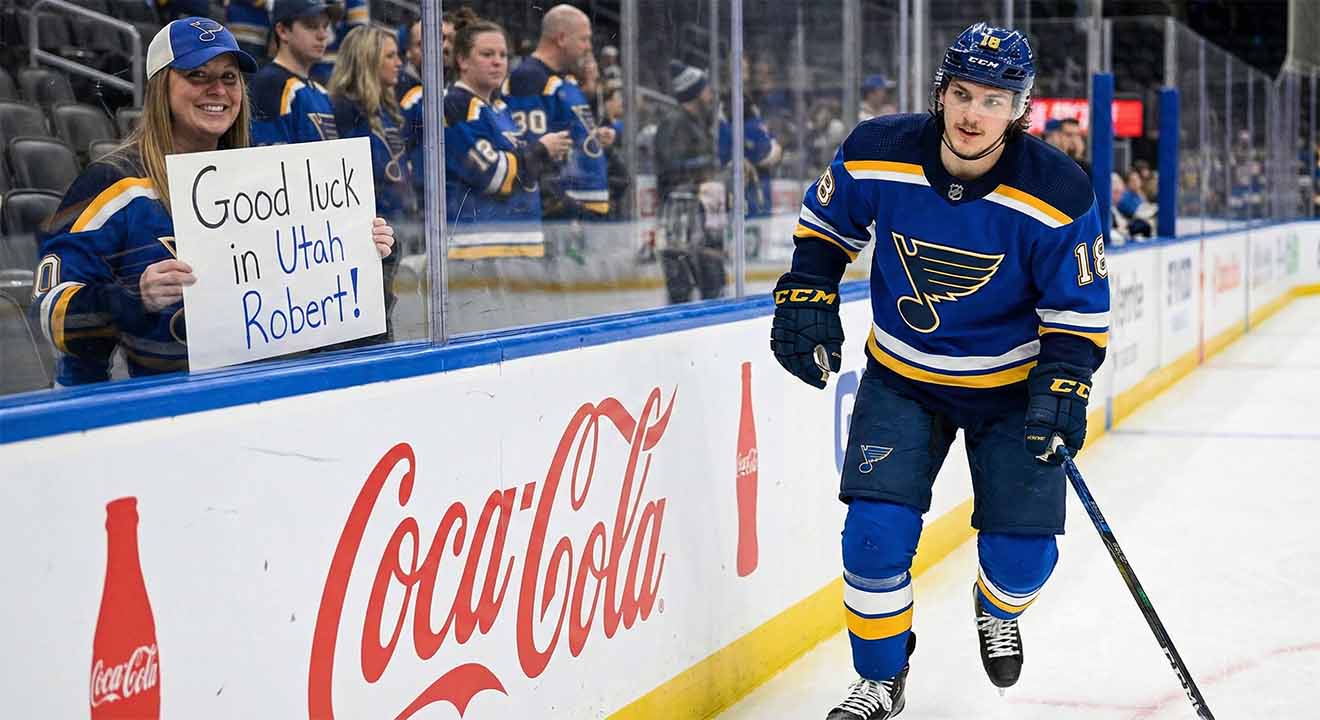 St. Louis Blues center Robert Thomas smiles as he skates past a female fan behind the glass holding a handmade sign that reads "Good luck in Utah Robert!" amidst heavy trade rumors involving the Utah Mammoth.