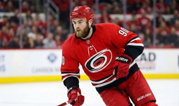 Nashville Predators center Ryan O'Reilly depicted in a red Carolina Hurricanes home uniform, skating with a puck during an NHL game.