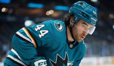 Kiefer Sherwood, wearing a teal San Jose Sharks uniform, looks over his shoulder on the ice amidst growing NHL trade deadline rumors regarding his future with the struggling team.