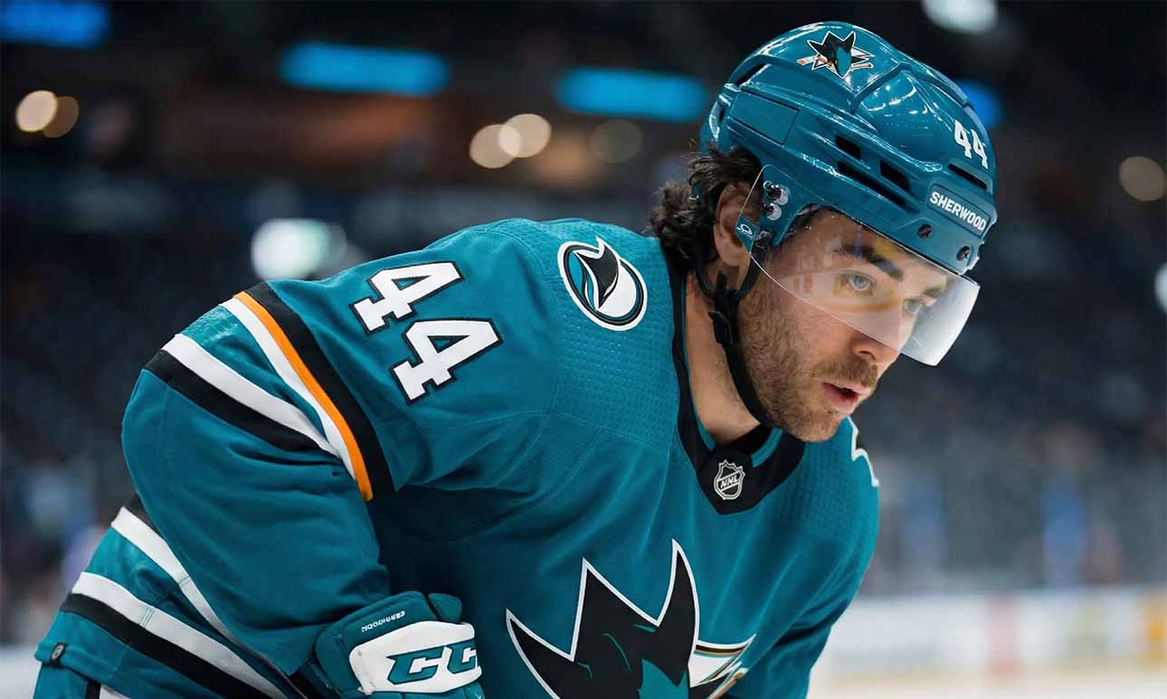 Kiefer Sherwood, wearing a teal San Jose Sharks uniform, looks over his shoulder on the ice amidst growing NHL trade deadline rumors regarding his future with the struggling team.