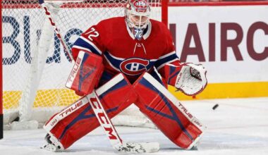 NHL goaltender Sergei Bobrovsky, wearing a red, white, and blue Montreal Canadiens uniform, pads, and mask, is in a butterfly stance on the ice in front of the net. His eyes are focused on a puck sliding on the ice to his right.