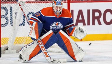 Sergei Bobrovsky crouched in a butterfly stance guarding the net, wearing a full Edmonton Oilers goaltender uniform including a blue and orange jersey, custom-painted mask, and matching pads with a puck visible near his glove.