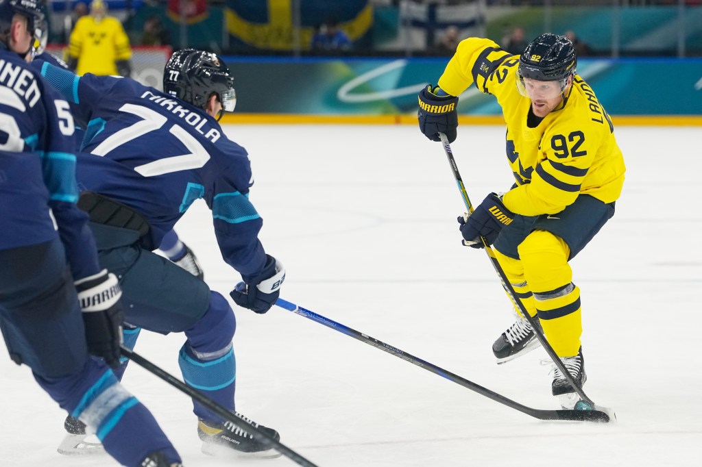 Sweden's Gabriel Landeskog (92) shoots the puck against Finland during a preliminary round match of men's ice hockey at the 2026 Winter Olympics.