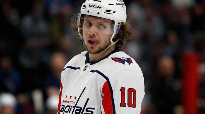 Artemi Panarin in a white Washington Capitals jersey and helmet, number 10, looking towards the right with his tongue out.